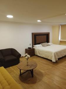 a bedroom with a bed and a couch and a table at Hotel Guadalupe Express in Guadalupe