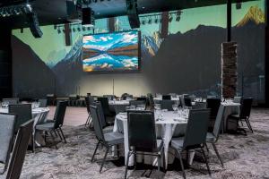 a conference room with tables and chairs and a large screen at Copper King Convention Center, an Ascend Collection Hotel in Butte