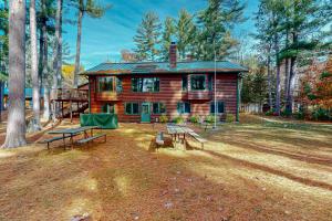 a log cabin with picnic tables in front of it at Camp Farrell in Manitowish Waters