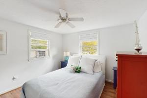 ein Schlafzimmer mit einem weißen Bett mit Deckenventilator in der Unterkunft The Kettle Cottage in Cotuit