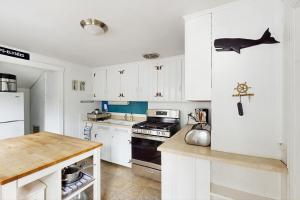 Eine Küche mit weißen Schränken und einem Haifischmagneten am Kühlschrank in der Unterkunft The Kettle Cottage in Cotuit