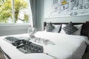 a bed with a tray of glasses and a swan on it at Beehive Phuket Old Town Hostel in Phuket Town +39 photos