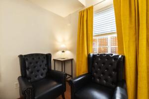 two black chairs next to a window with yellow curtains at Snowcreek Suite - Aspen - Hot Tub - Kitchenette in Leavenworth