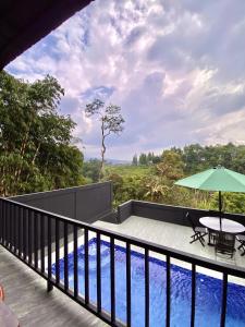 a balcony with a table and an umbrella and a pool at Deju Cabin with Private Pool & Mountain View in Cilama
