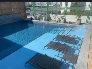 a swimming pool with four chairs in a building at Beautiful Apartment cop30 in Belém