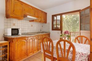 eine Küche mit Holzschränken und einem Tisch mit Mikrowelle in der Unterkunft Holiday Cottage Santa Lucía 1 in Santa Lucía