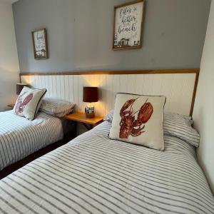 a bedroom with two beds and a table with a pillow at Rock Lobster in Camber