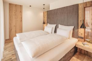 a bedroom with a large white bed with white pillows at Apartments Silva Living in San Giovanni in Val Aurina