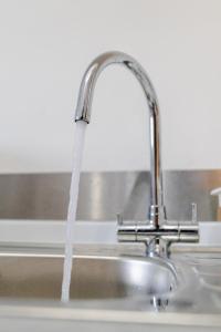 eine Küchenspüle mit Wasser aus einem Wasserhahn in der Unterkunft Modern 1-BR Apartment near Cardiff City Centre in Cardiff