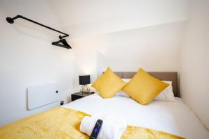 ein Schlafzimmer mit einem Bett mit gelben Kissen in der Unterkunft Modern 1-BR Apartment near Cardiff City Centre in Cardiff