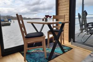 a table with two chairs and a glass of wine at Hausboot Am See in Rieth +12 photos