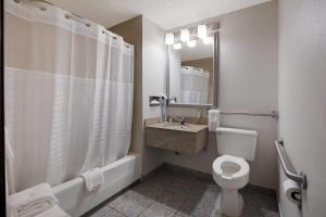 a bathroom with a toilet and a sink and a shower at Quality Inn Hall of Fame in Canton +23 photos