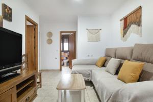 a living room with a couch and a tv at Villa Fornell 1 piscina compartida in Conil de la Frontera