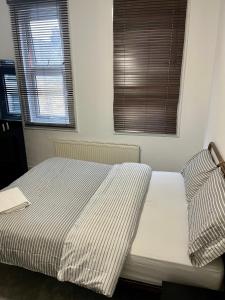 ein Schlafzimmer mit einem Bett mit gestreifter Bettwäsche und zwei Fenstern in der Unterkunft Home from home in Southend-on-Sea