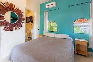 Un dormitorio con una cama y una pared azul. en Hostel La Botella de Leche - Tamarindo, en Tamarindo 42 fotos más