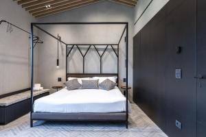 een slaapkamer met een zwart hemelbed met witte lakens bij Suite Fattore in San Gimignano