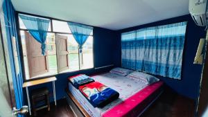 a bedroom with a bed with blue walls and windows at Happy Fuji Homestay in Ko Phrao Nai