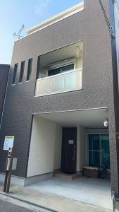 a brown brick building with a door and a window at Kasilin House in Osaka