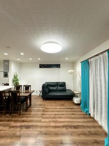 a living room with a black couch and a table at Kasilin House in Osaka