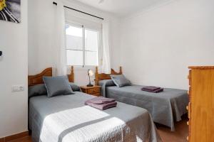 a bedroom with two beds and a window at Apartamento Azucenas in Conil de la Frontera