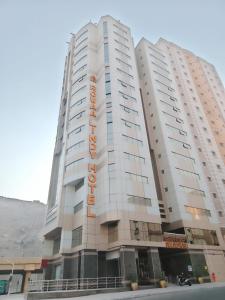 a tall white building with an orange sign on it at Rowaa Lindy Hotel Makkah in Makkah