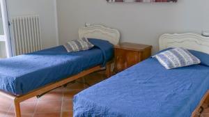 two beds in a room with blue sheets and pillows at Cascina Solaro in Asti +19 photos