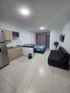 a living room with a couch and a kitchen and a bed at Apartaestudio 101 cómodo y Moderno in Tuluá