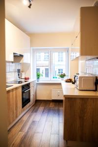 a kitchen with wooden floors and a large window at Apartamenty Szlachecki i Pod Artusem in Gdańsk