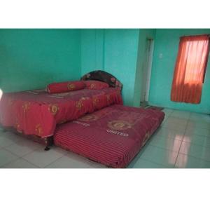 a bedroom with two beds with red sheets at Hotel O Nany Asoka Syariah Near Anyong Cafe Studio in Medan