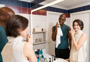 ウィーンにあるvoco Vienna Prater by IHGのバスルームで歯を磨いている男性と女性