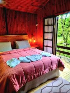 um quarto com uma cama com um edredom vermelho em Pousada Bramasole em Monte Verde