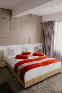 a bedroom with a large white bed with red pillows at Hotel Koncept Residence in Sarajevo