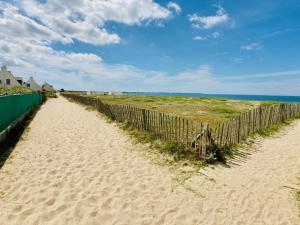 a fence on a sandy beach next to the ocean at Kerann 1mn de la plage avec jardin in La Turballe
