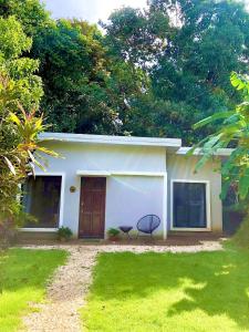 een klein wit huis met een stoel ervoor bij Private Costa Rican Oasis with Pool River Views in Montezuma