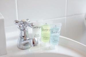 Ein Waschbecken im Badezimmer mit einer Flasche Lotion und einem Wasserhahn in der Unterkunft Blue Lagoon Retreat Escape Free Parking 14ppl in Sheffield + 64 Fotos