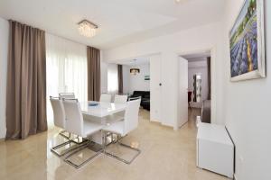 biała jadalnia z białym stołem i krzesłami w obiekcie Luxury Apartment 1 Villa Arta w Bibinje