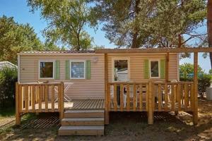 a tiny house with a large wooden deck at Camping Cœur de Vendée in La Boissière-de-Montaigu