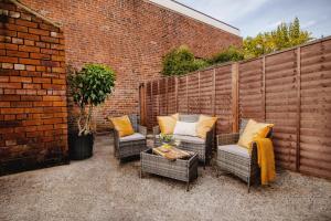 eine Terrasse mit Korbstühlen, einem Tisch und einer Ziegelwand in der Unterkunft Blue Lagoon Retreat Escape Free Parking 14ppl in Sheffield