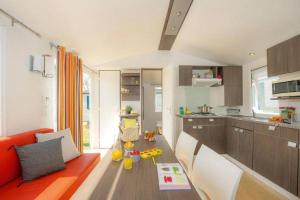 a living room with an orange couch and a table at Camping Cœur de Vendée in La Boissière-de-Montaigu