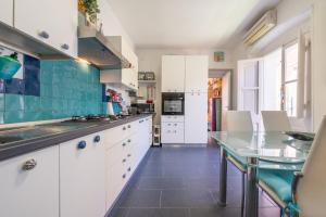 a kitchen with white cabinets and a glass table at Casa Nora in Calasetta