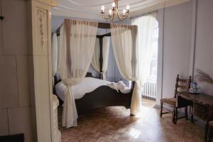 a bedroom with a canopy bed with white curtains at Jaunpils pils in Jaunpils