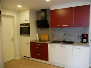 a kitchen with red and white cabinets and a sink at Am Kiefernweg 17 in Schwielochsee +11 photos
