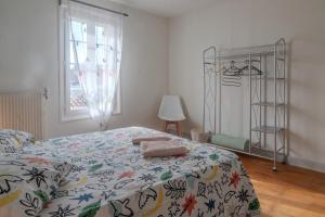 a bedroom with a bed with a comforter and a window at Les Hirondelles Archiac in Archiac