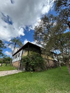a white building with a balcony on a grass field at Estalagem Angu Duro in São Gonçalo do Rio das Pedras