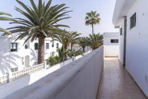 Elle comprend un balcon avec des palmiers et un mur blanc. dans l'établissement Piso Dunas Blu - Carpe Mundi, à Corralejo