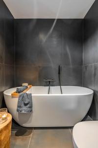 y baño con bañera blanca y azulejos negros. en Lofoten Oceanfront Panoramic, en Kabelvåg