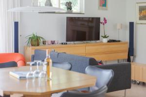 ein Wohnzimmer mit Tisch und Fernseher in der Unterkunft Duinvilla Deluxe met Sauna en Whirpool - 6 personen in Holle Poarte