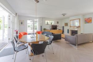 ein Esszimmer und ein Wohnzimmer mit Tisch und Stühlen in der Unterkunft Duinvilla Deluxe met Sauna en Whirpool - 6 personen in Holle Poarte