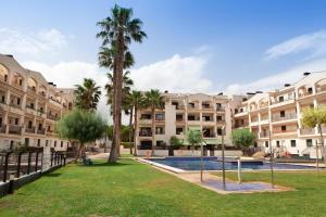 a courtyard with palm trees and a large building at Apartamento La Cala Azul en Miami in Miami Platja