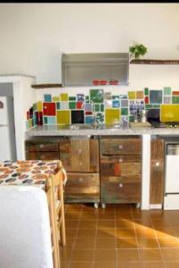 a kitchen with a counter with colorful tiles on the wall at Casa Baia in Capo Testa +19 photos